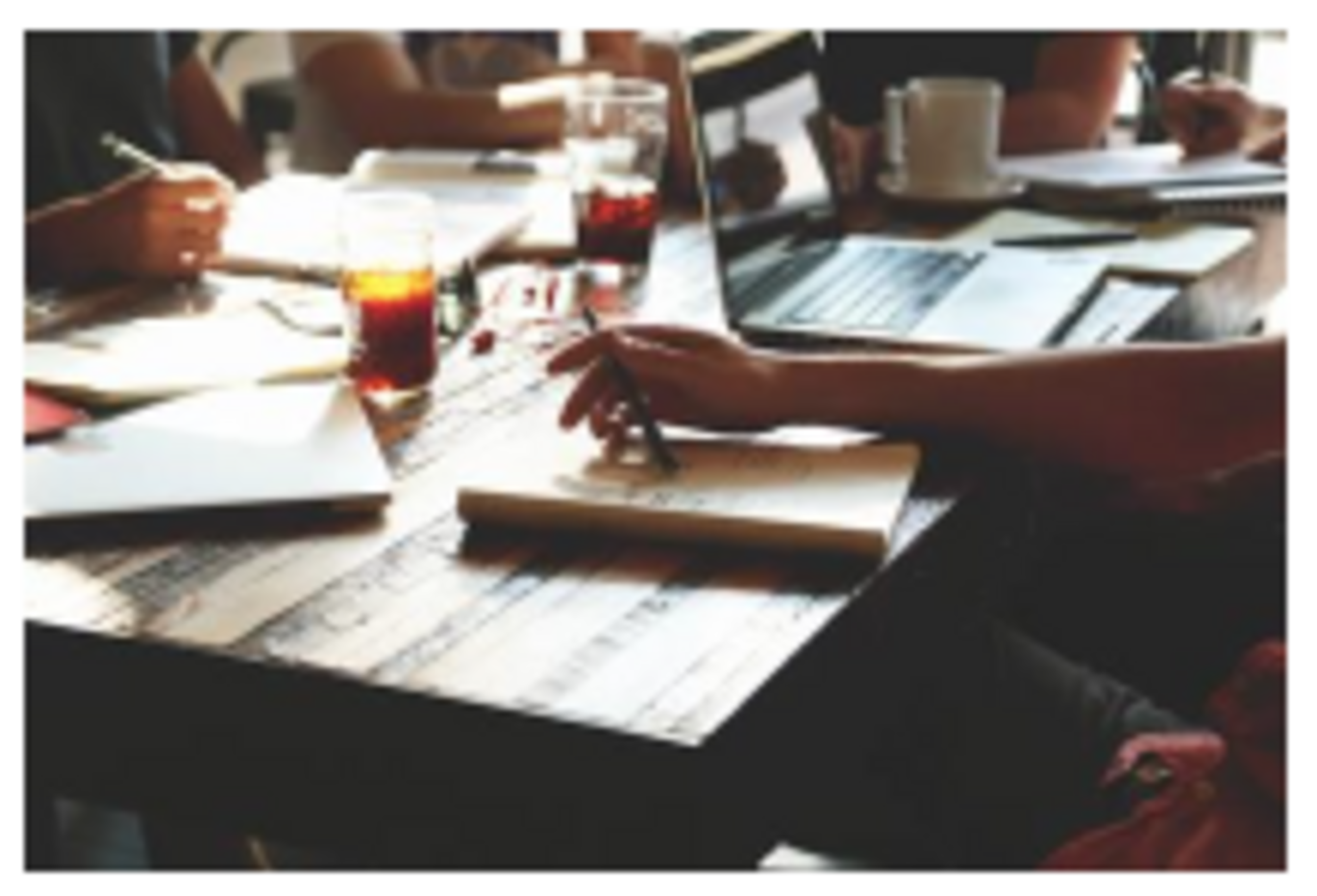 Photo of people with coffee and laptops around a meeting table